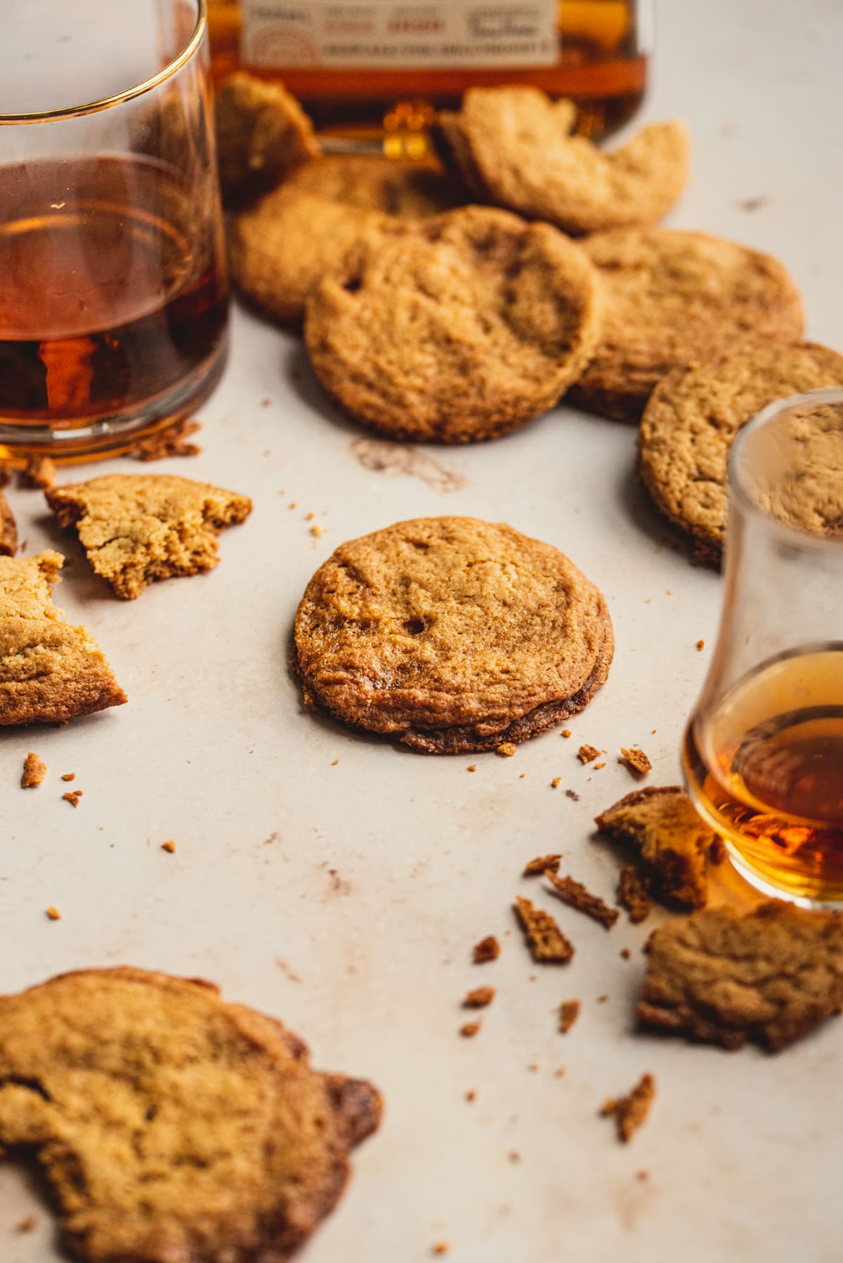 caramel cookies on a brown table with glasses of bourbon surrounding.