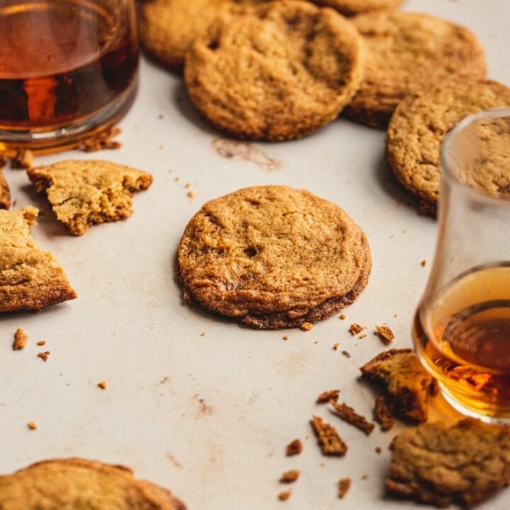 caramel cookies on a brown table with glasses of bourbon surrounding.