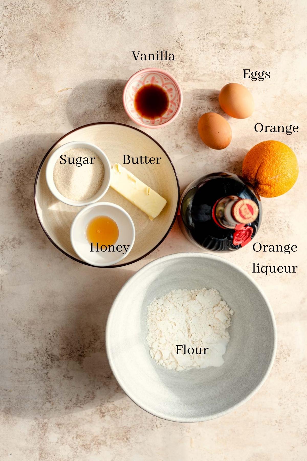 Ingredients for orange madeleines tabled on table.