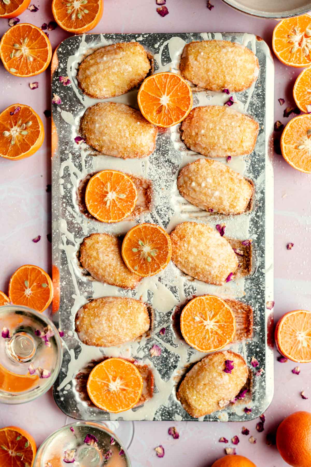 French orange madeleines in a mold with cut oranges scattered.