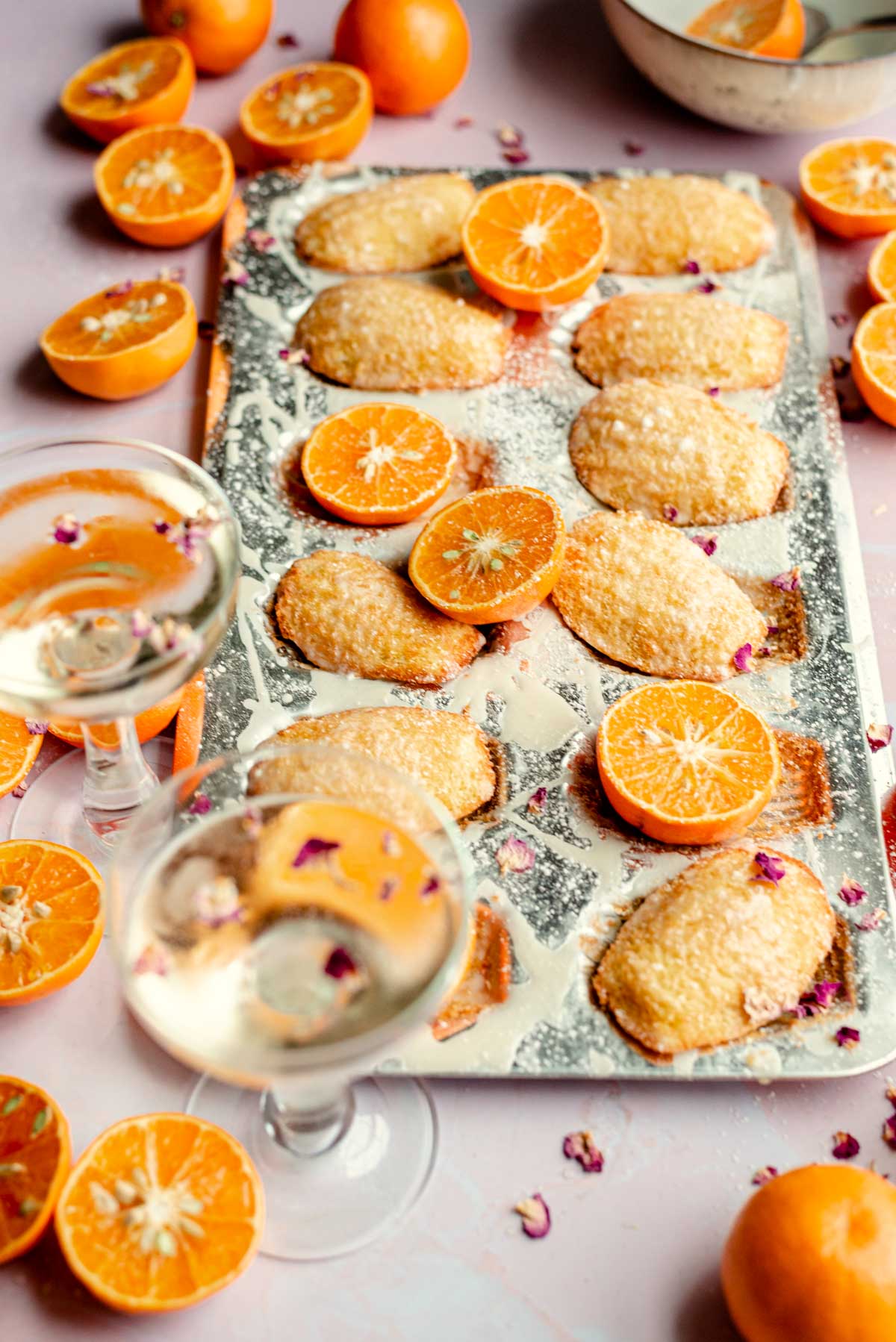 French orange madeleines in a mold with cut oranges scattered.