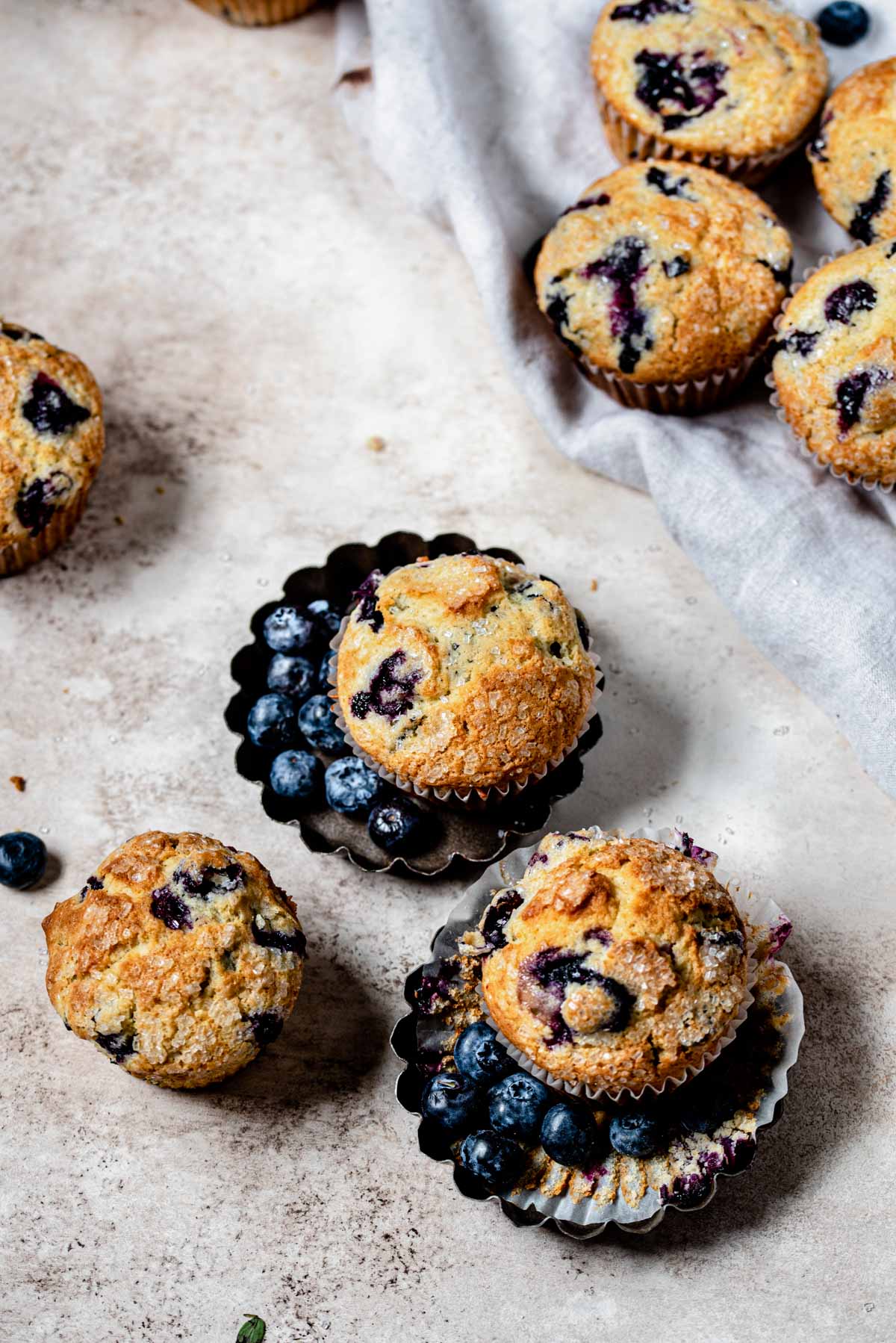 Overhead shot of blueberry muffins scattered on a brown table.