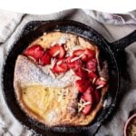 Dutch Baby in a cast iron skillet with fresh strawberries
