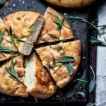 Sliced focaccia bread on a upside down baking sheet and sprinkled with sage.