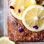 Lemon Cardamom Olive oil cake on a wooden cutting board with lemon slices on top.
