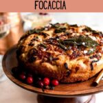 Focaccia topped with brown butter, sage, and caramelized onions on top of a wood cake stand