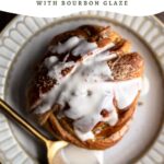 Cardamom bun with bourbon glaze drizzled on top on a plate with a spoon