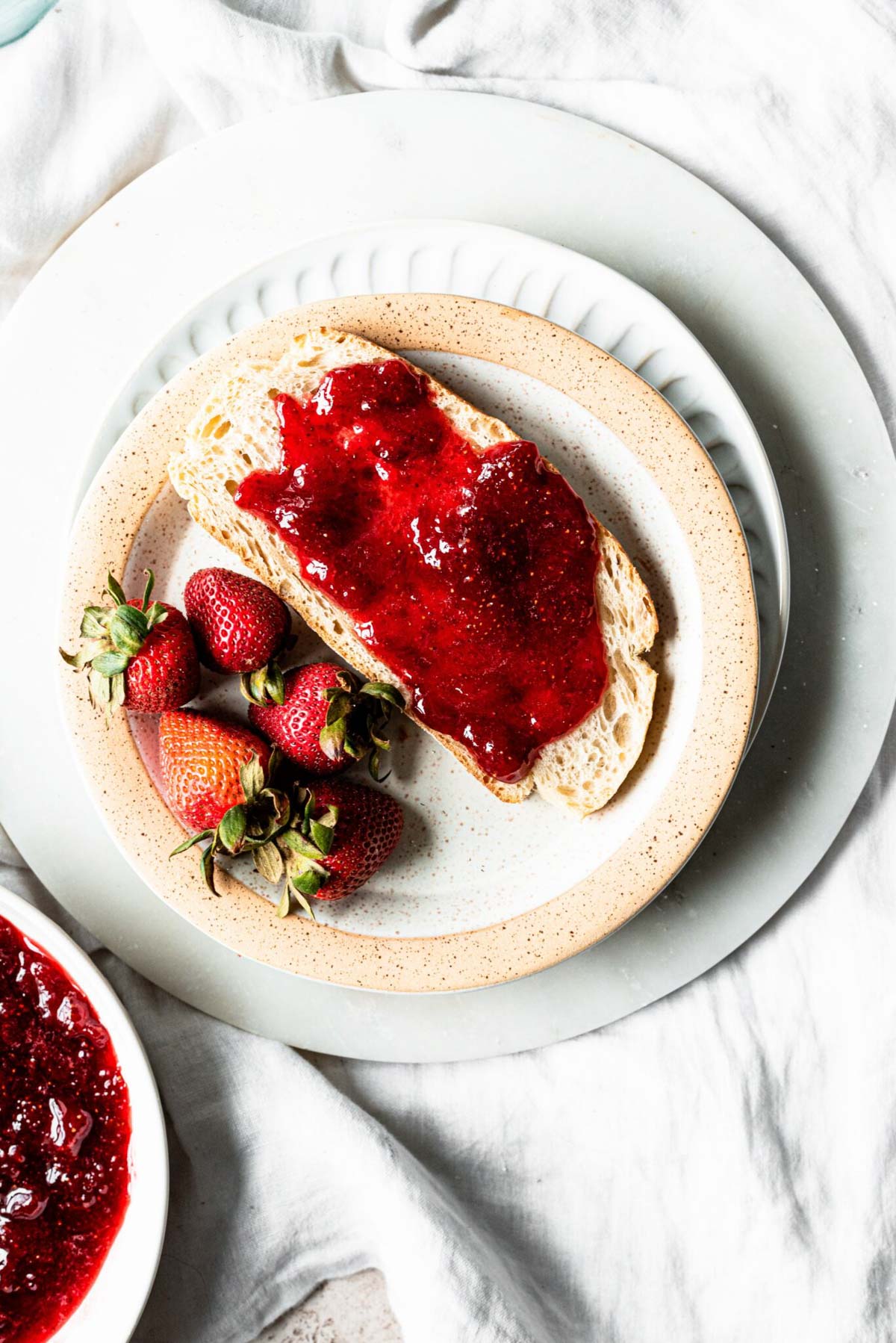 Toast with strawberry bourbon jam on a white plate on a marble tray.