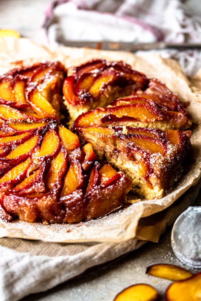 Cut Bourbon Peach Upside Down Cake on parchment paper with peach slices