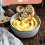 Honey butter in a grey bowl with a piece of bread in the butter
