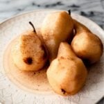 Poached pears cooling on a white plate.