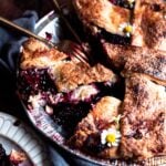 pie tin with blackberry pie with a fork and knife on top
