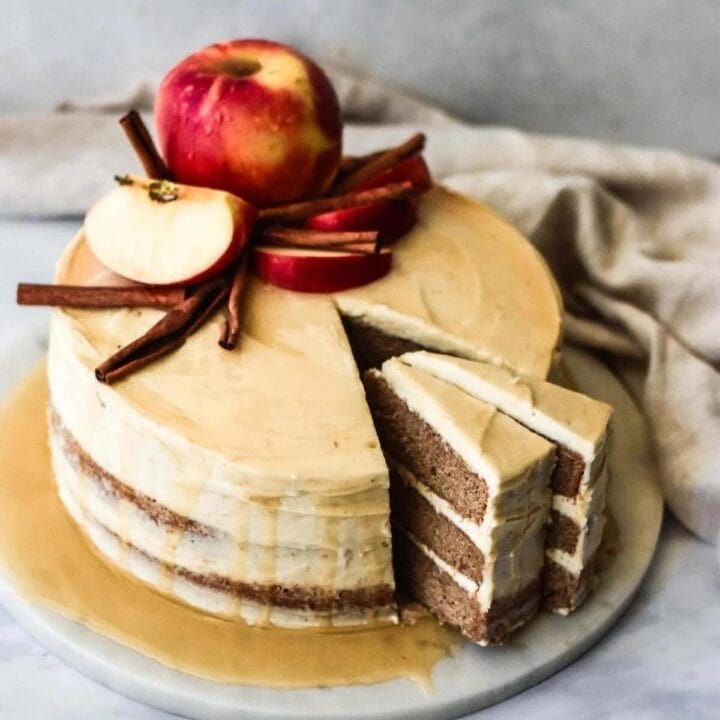 Apple cider layer cake on a marble tray and decorated with apples.