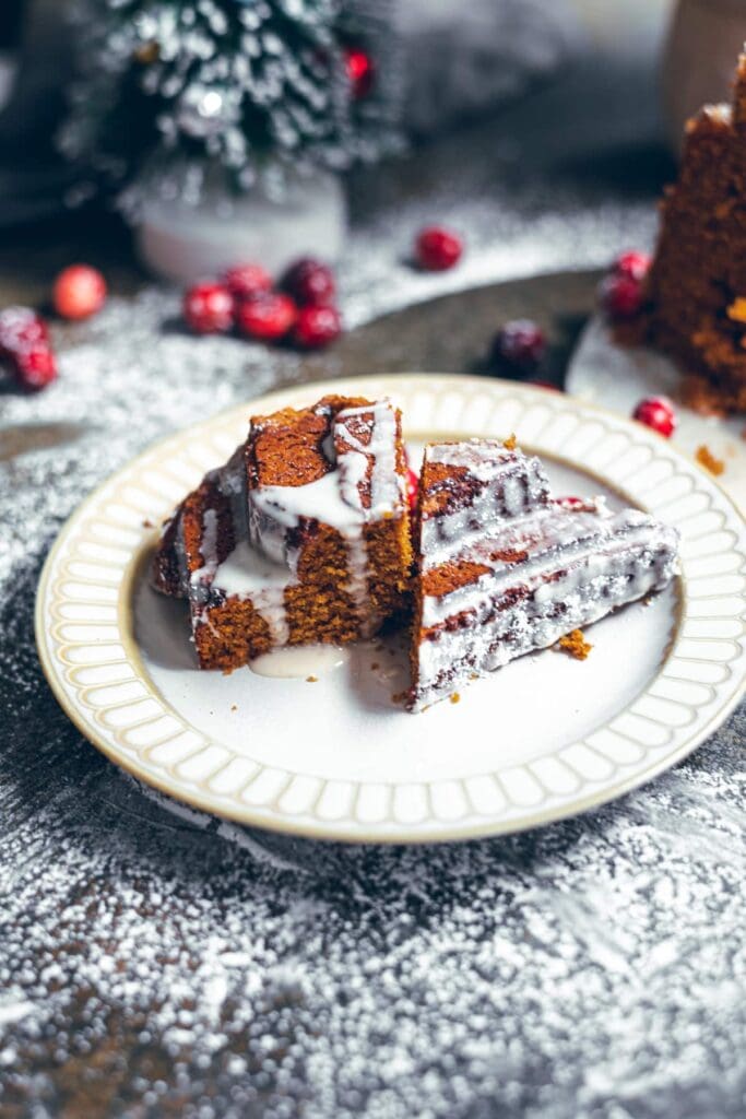 Sliced gingerbread cake on a nude plate dusted with powdered sugar.