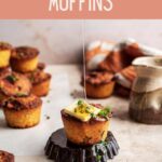 Bacon cornbread muffin topped with butter and chives on a brown table.