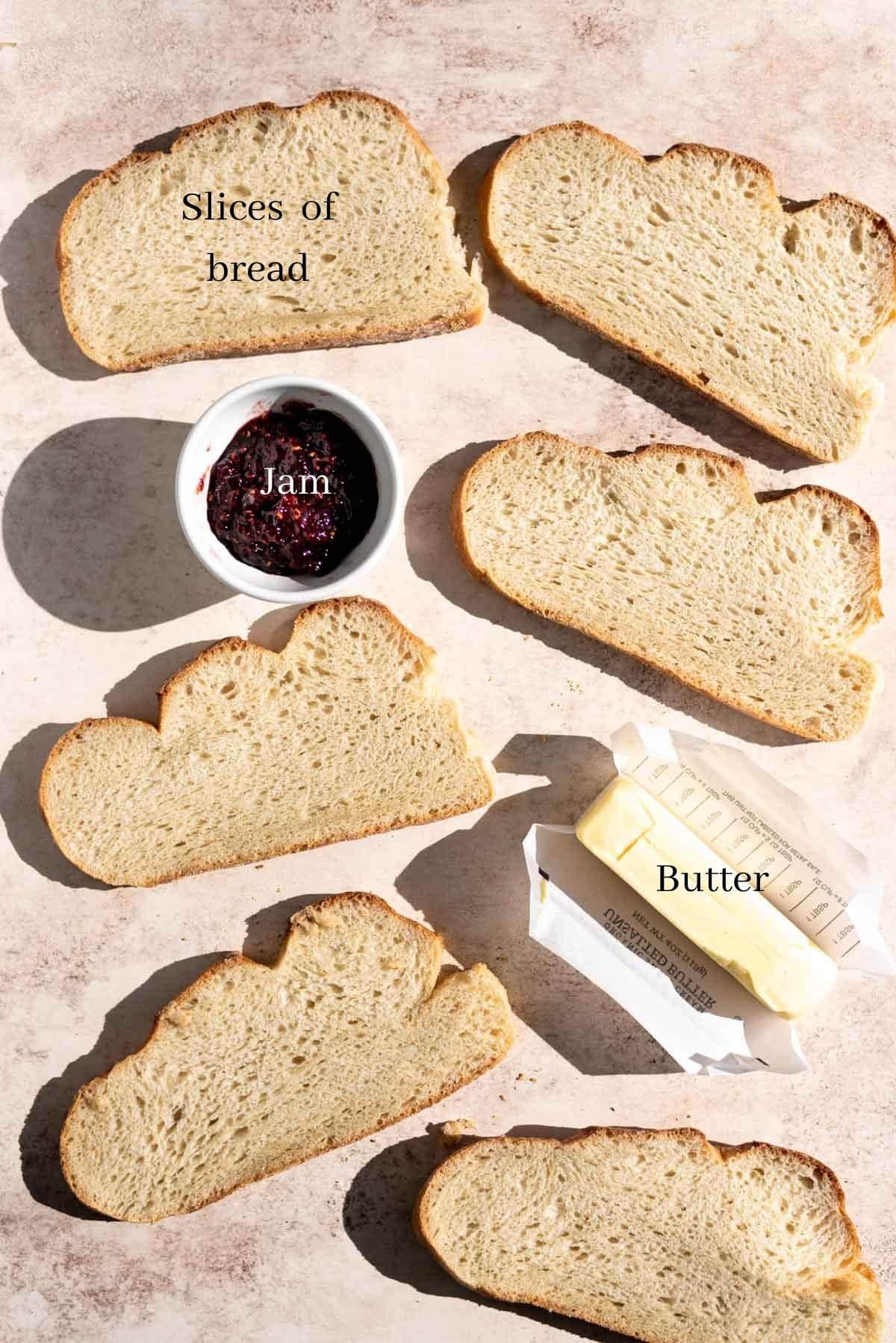 Ingredients, bread slices, butter, jam, on a brown table.