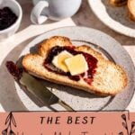 oasted bread on a speckled plate with jam and two slices of butter on top.