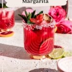 Blood orange margarita in a glass with a salted rim garnished with mint and blood orange cut into the shape of a heart.