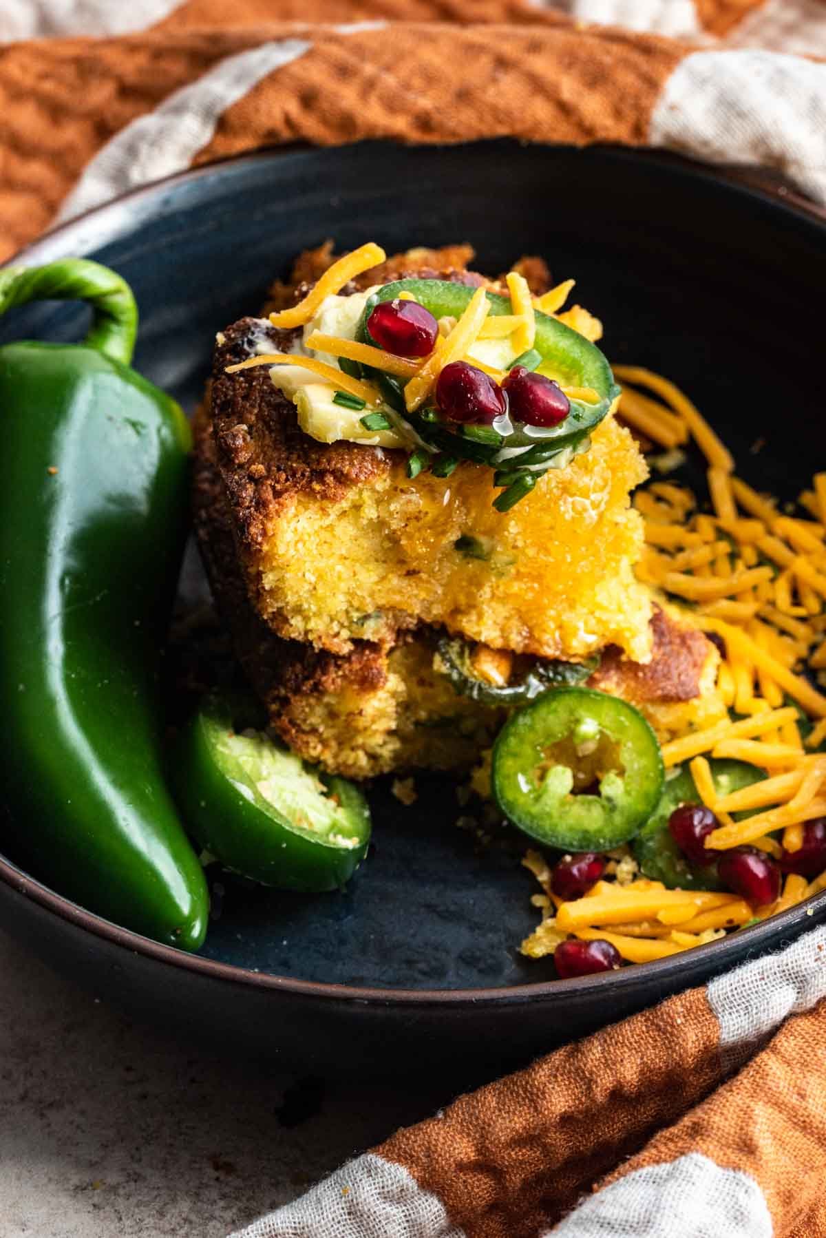 two slices of jalapeño cornbread stacked on top of each other topped with jalapeño slices.