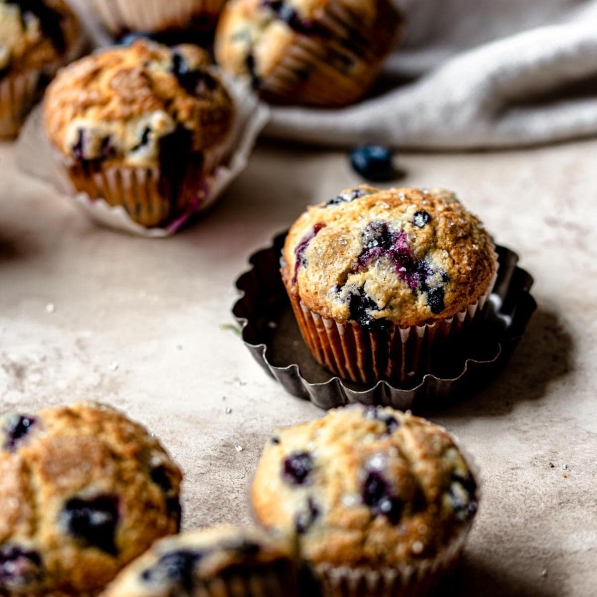Blueberry muffins scattered on a brown table.