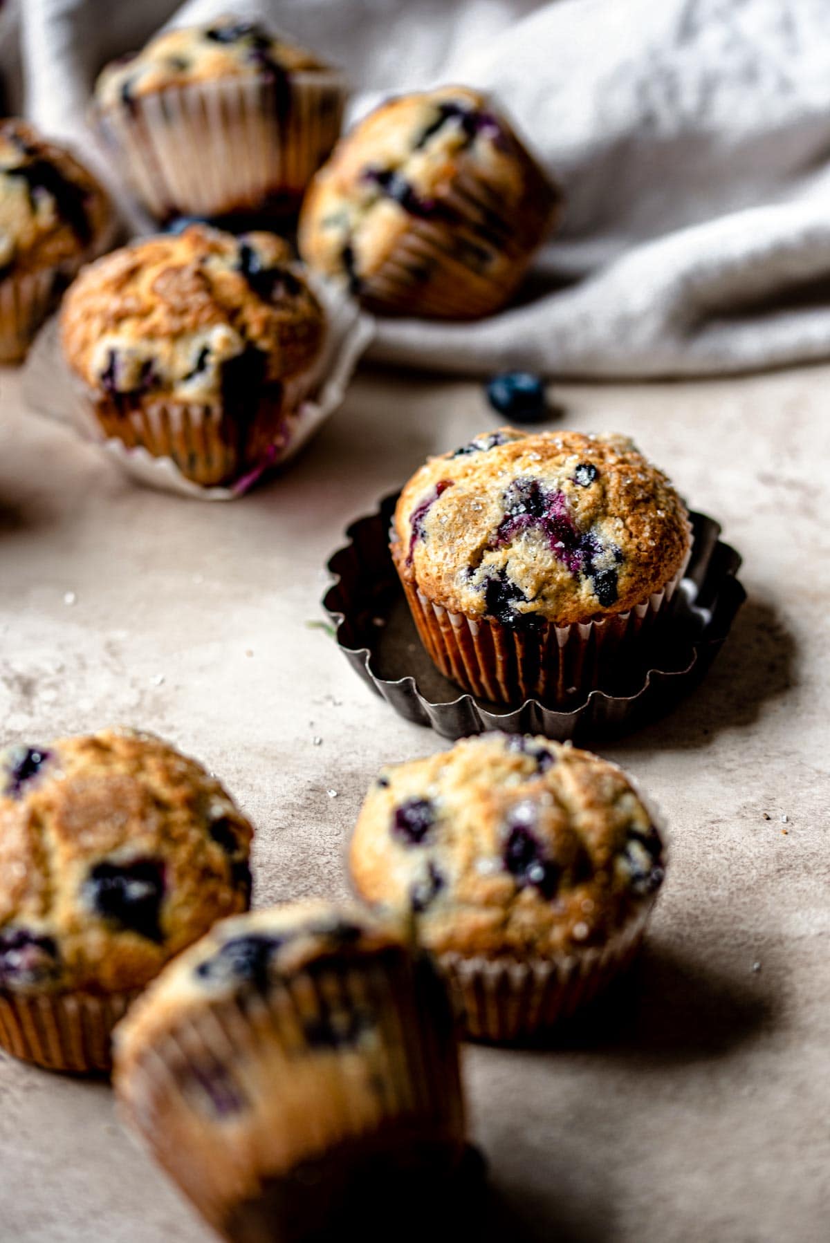Blueberry muffins scattered on a brown table.