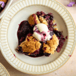 Blueberry cobbler in a bowl with a scoop of ice cream.