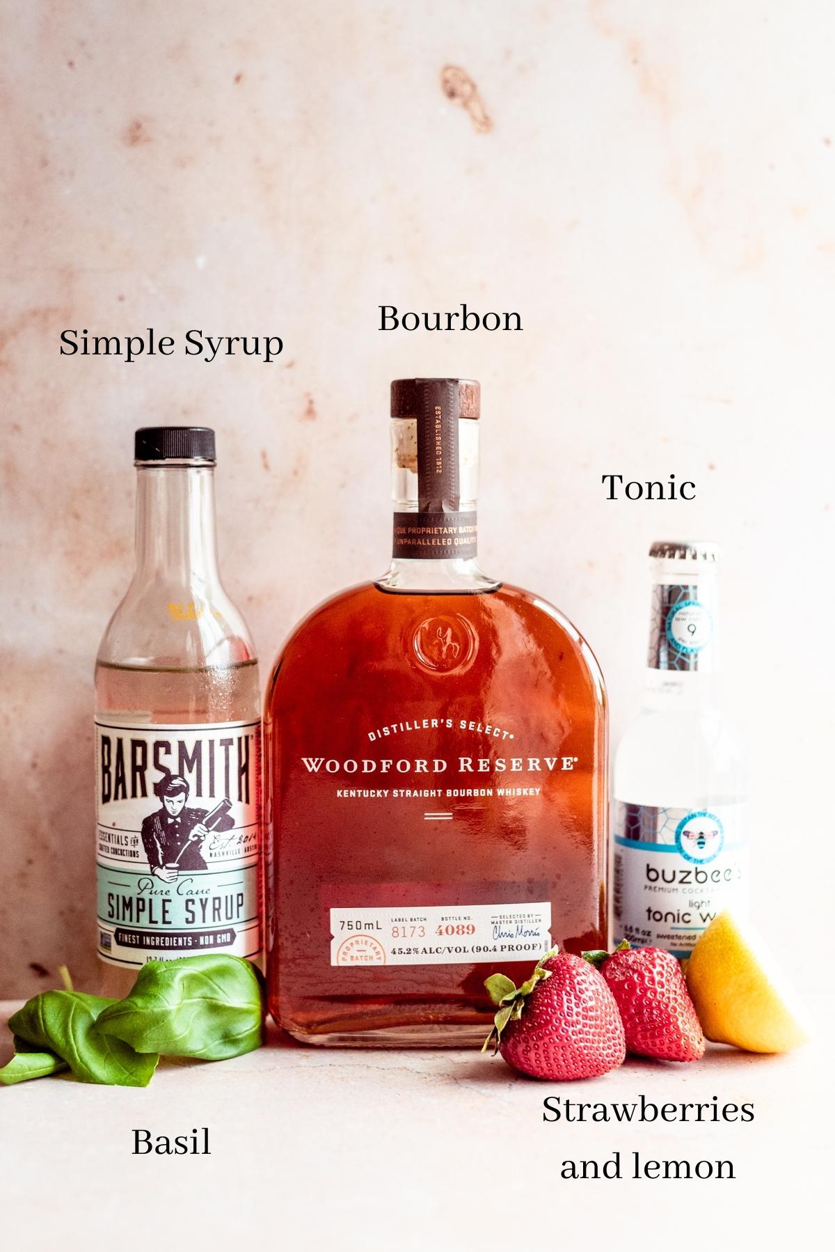 Ingredients for strawberry bourbon cocktail on a brown table.