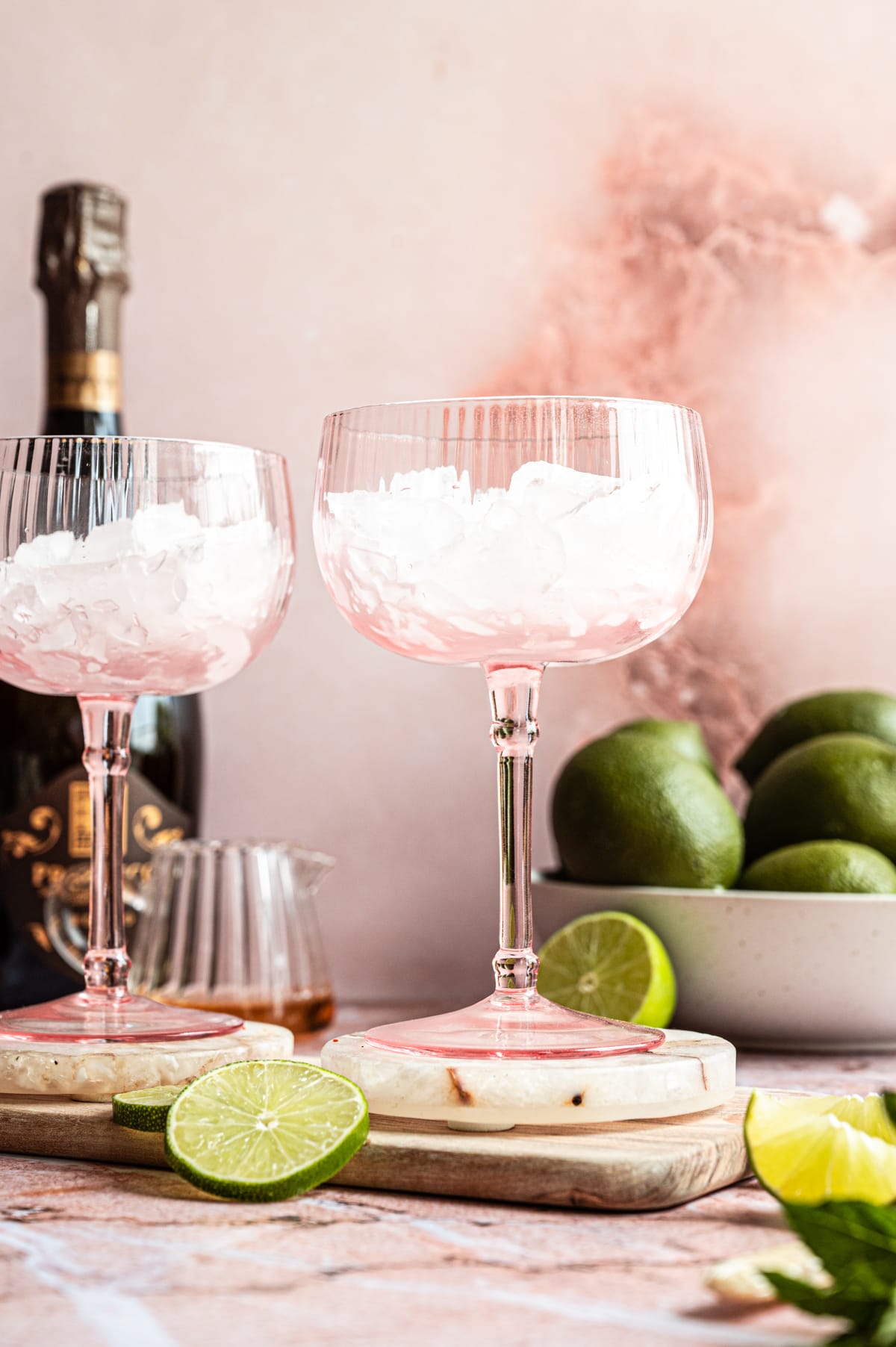 Two large pink coupe glasses filled with crushed ice.