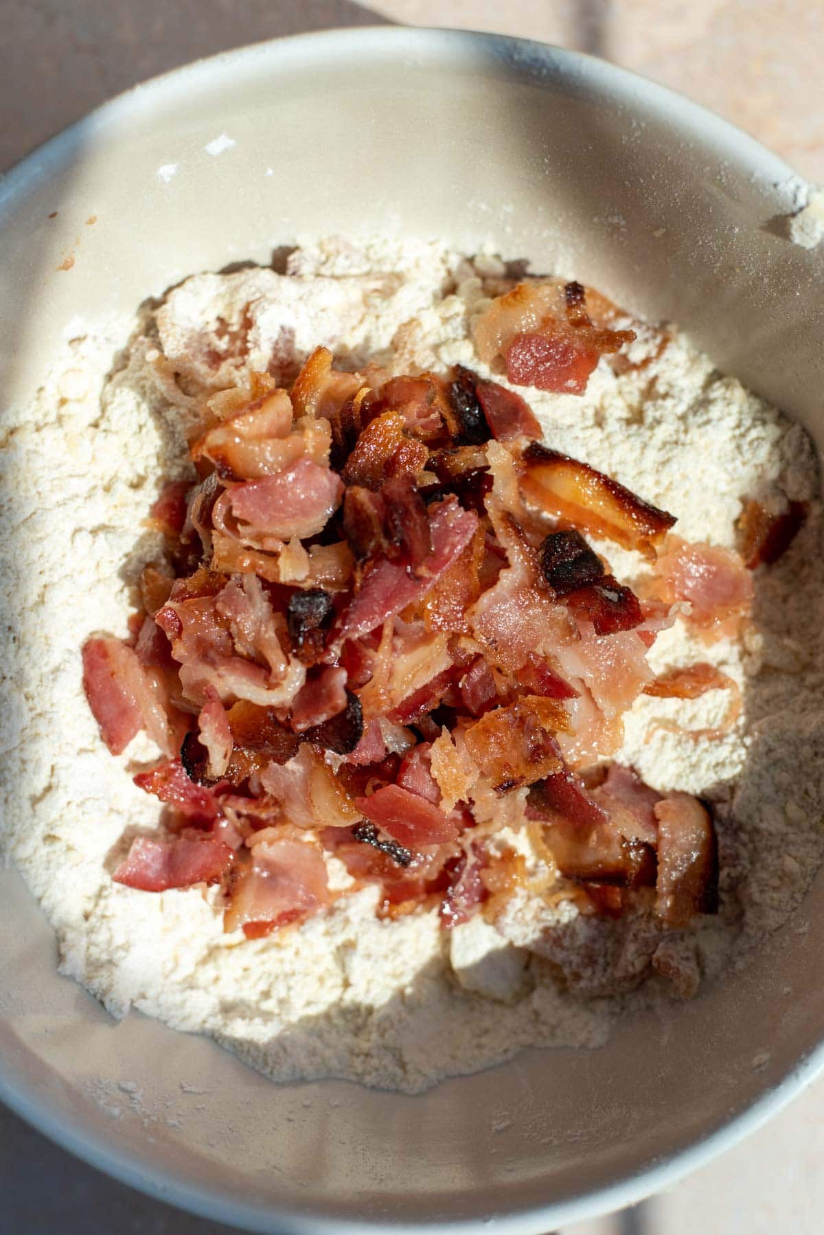A large mixing bowl full of the flour and topped off with the glazed bacon.