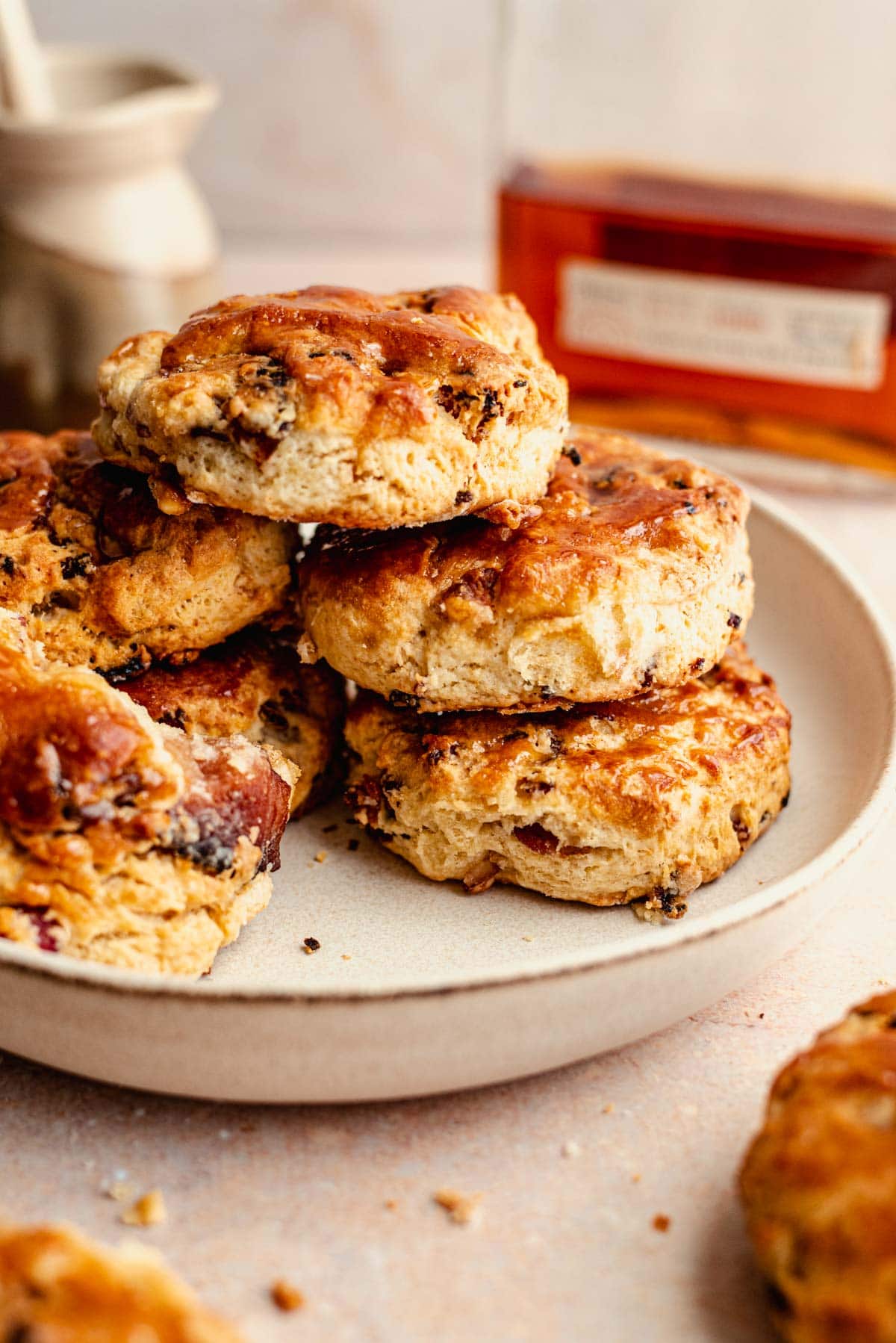 Stacked biscuits in a bowl bowl with a bottle of bourbon placed behind.