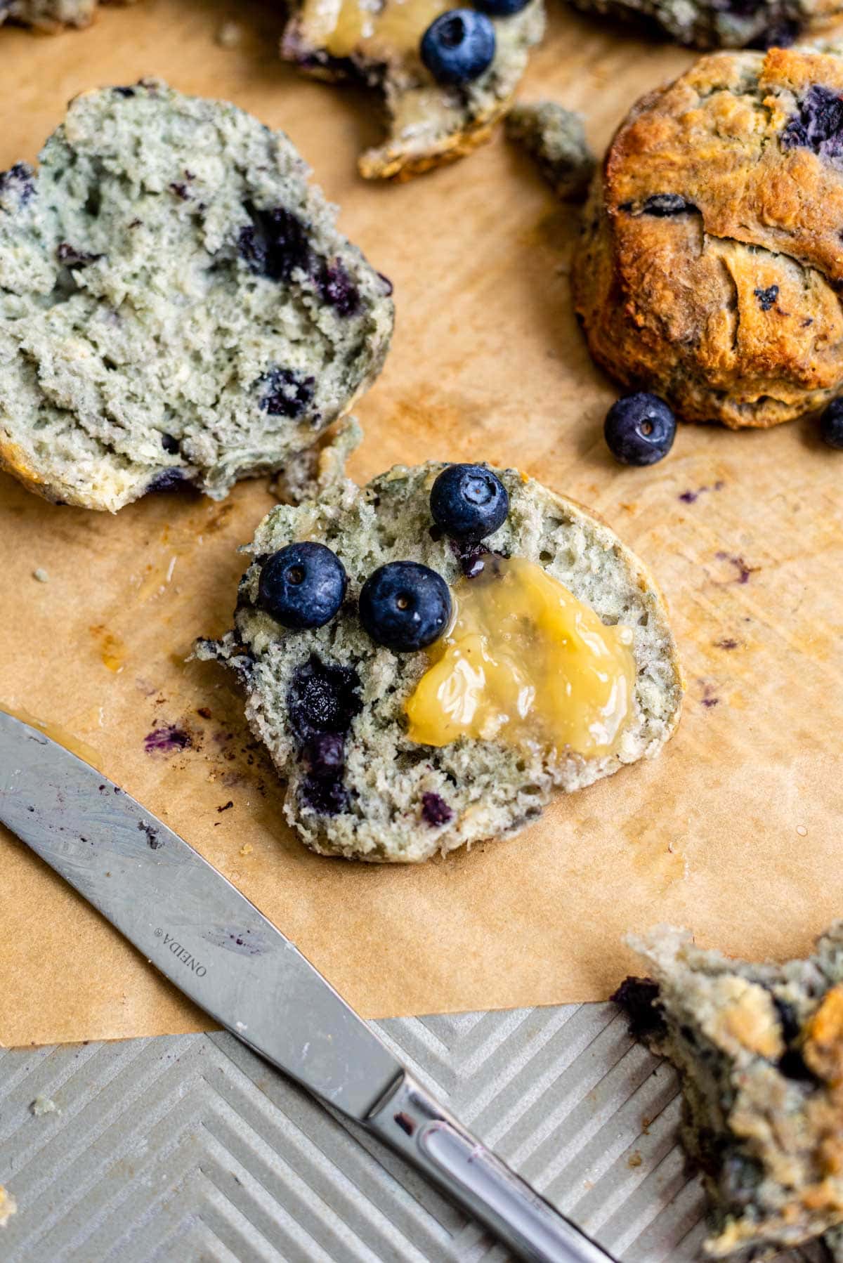 A sliced blueberry biscuit with lemon curd on brown parchment.