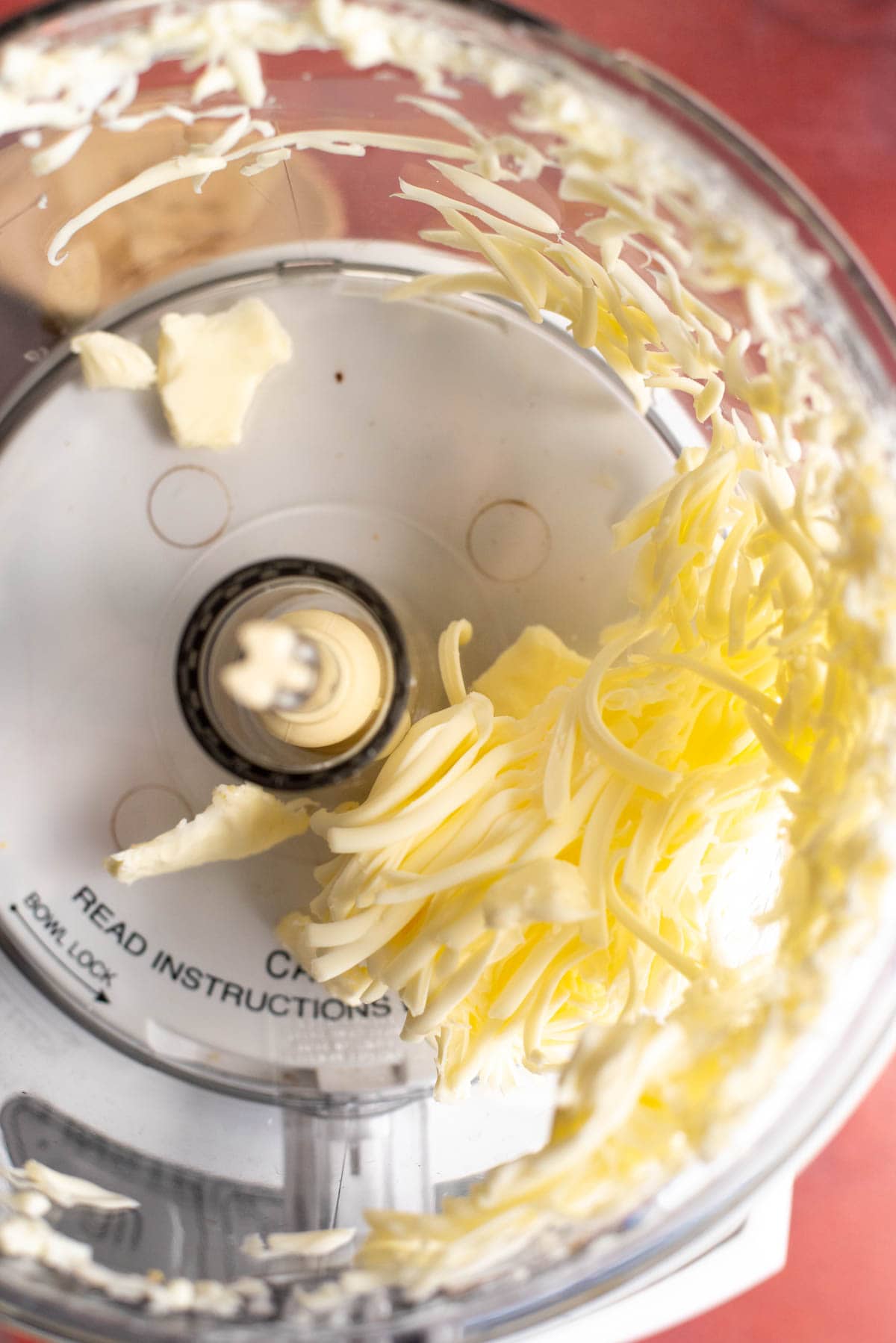 A food processor with grated butter in the bowl.