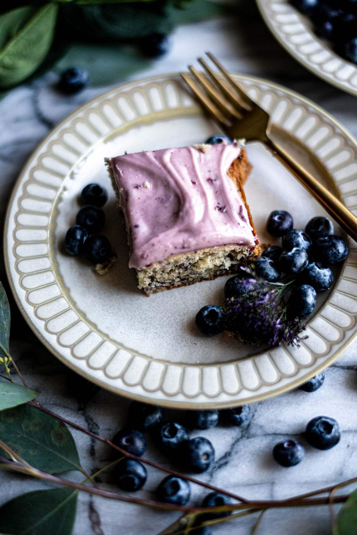 Slice of blueberry sheet cake on a plate with blueberries.