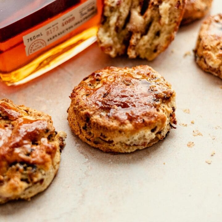 Biscuits on a brown stone table with a bottle of bout angled behind.