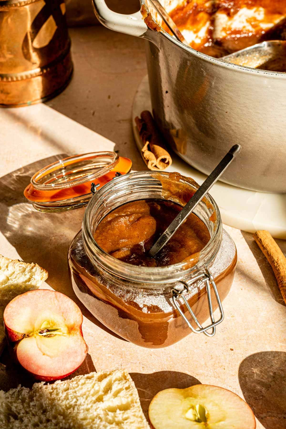 A jar with the apple butter with the dutch oven off to the side.