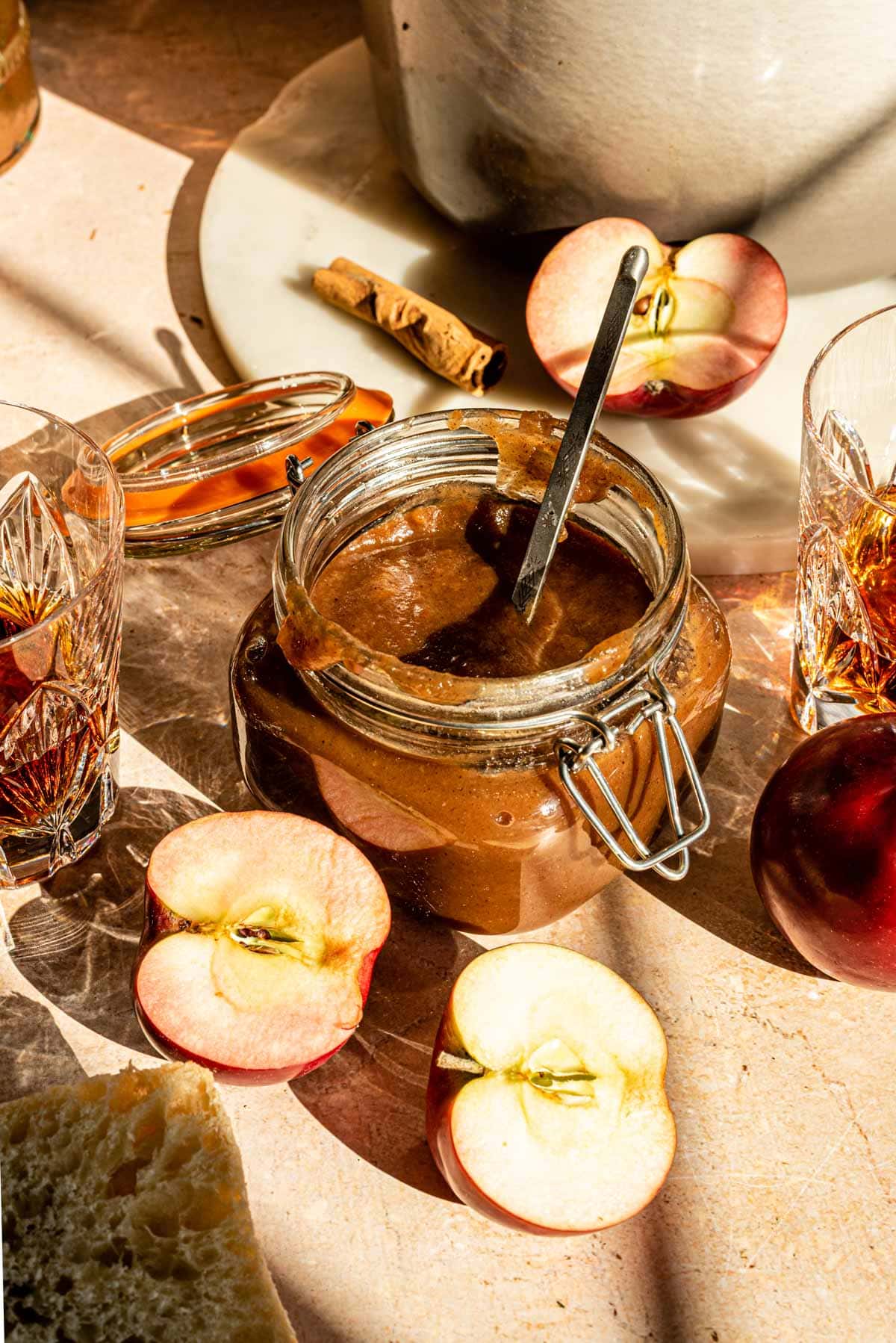 Apple butter in a glass jar with sliced apples off to the side.