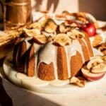Apple Butter Pound cake on a marble slab with an apple glaze. Its then topped with dried apple slices and is on a brown stone background.