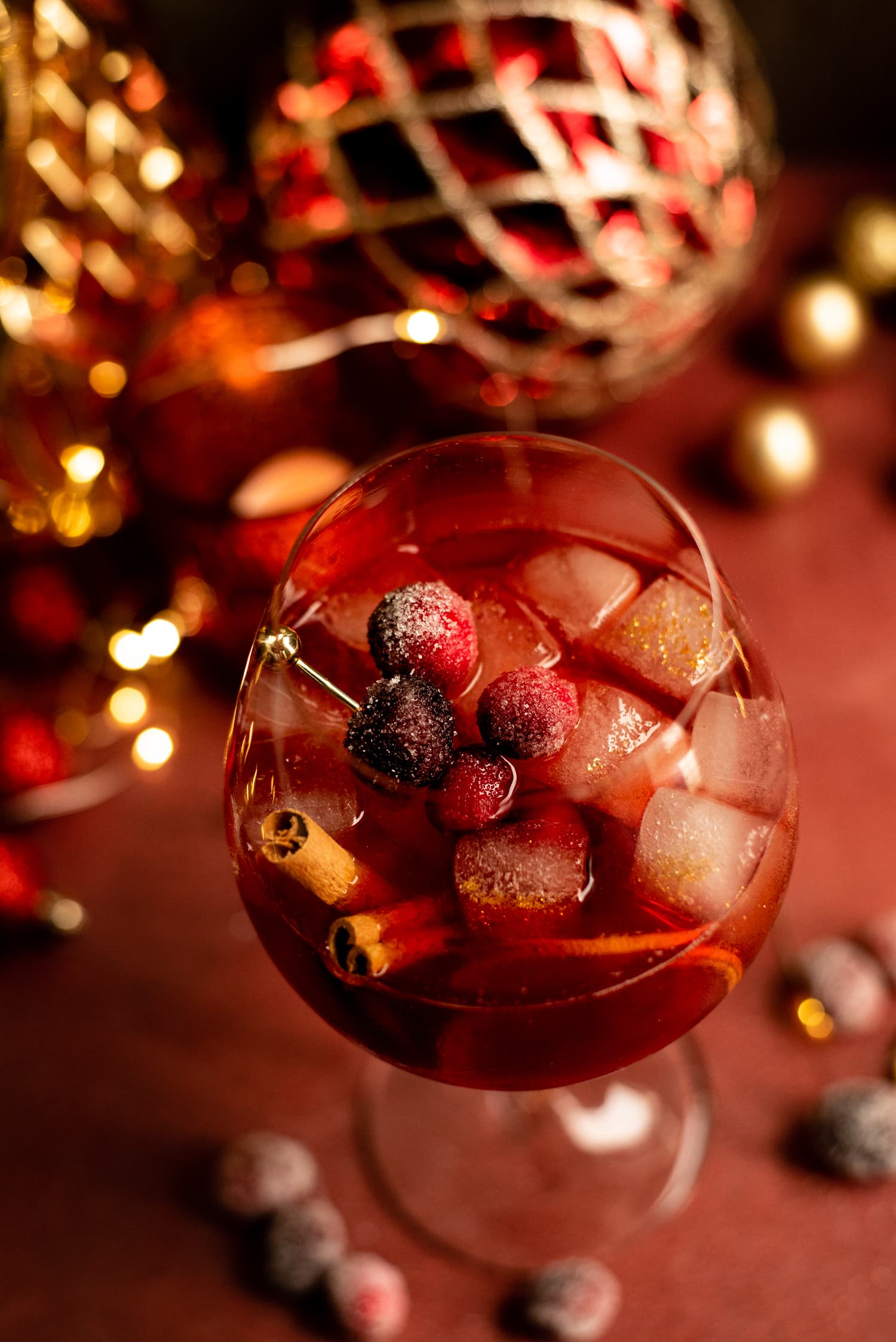 Overhead shot of a cranberry aperol sprtiz with old glitter ice, cranberries and cinnamon sticks.