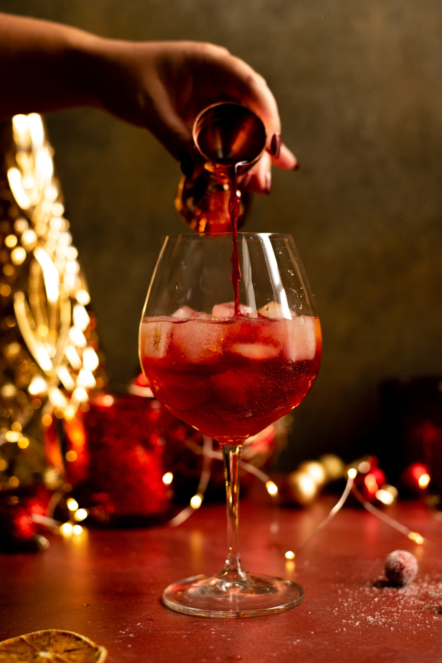 The cranberry juice being added to the cocktail.