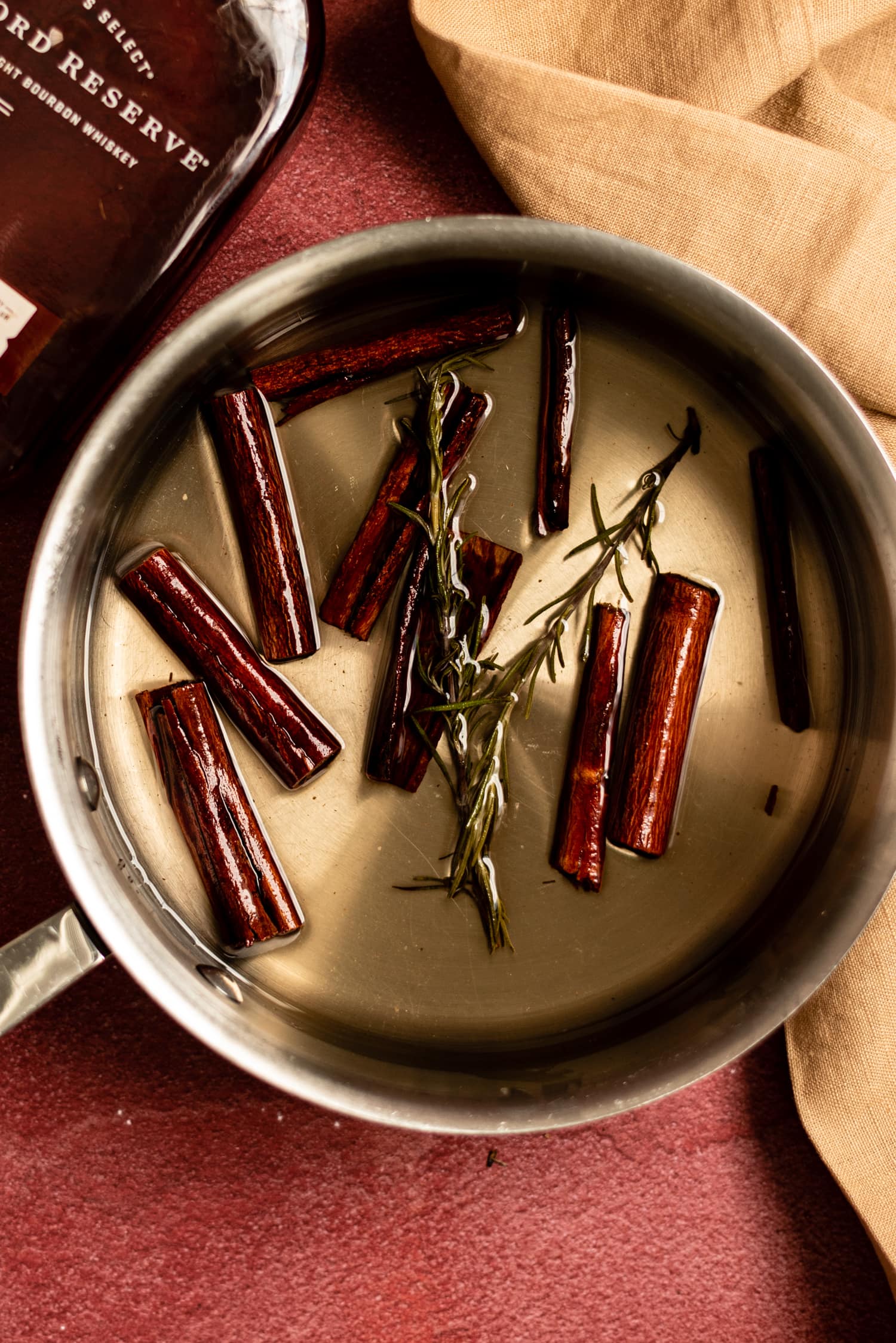 Saucepan with prepared syrup and with cinnamon sticks and rosemary. 