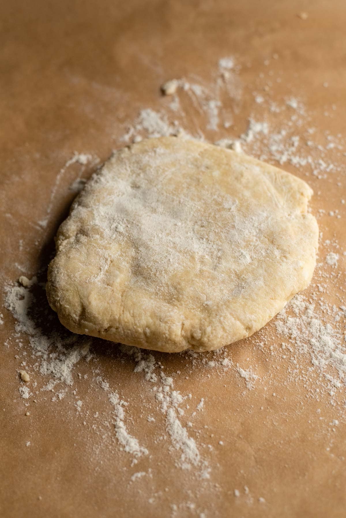 Kneaded pie dough on floured parchment paper.