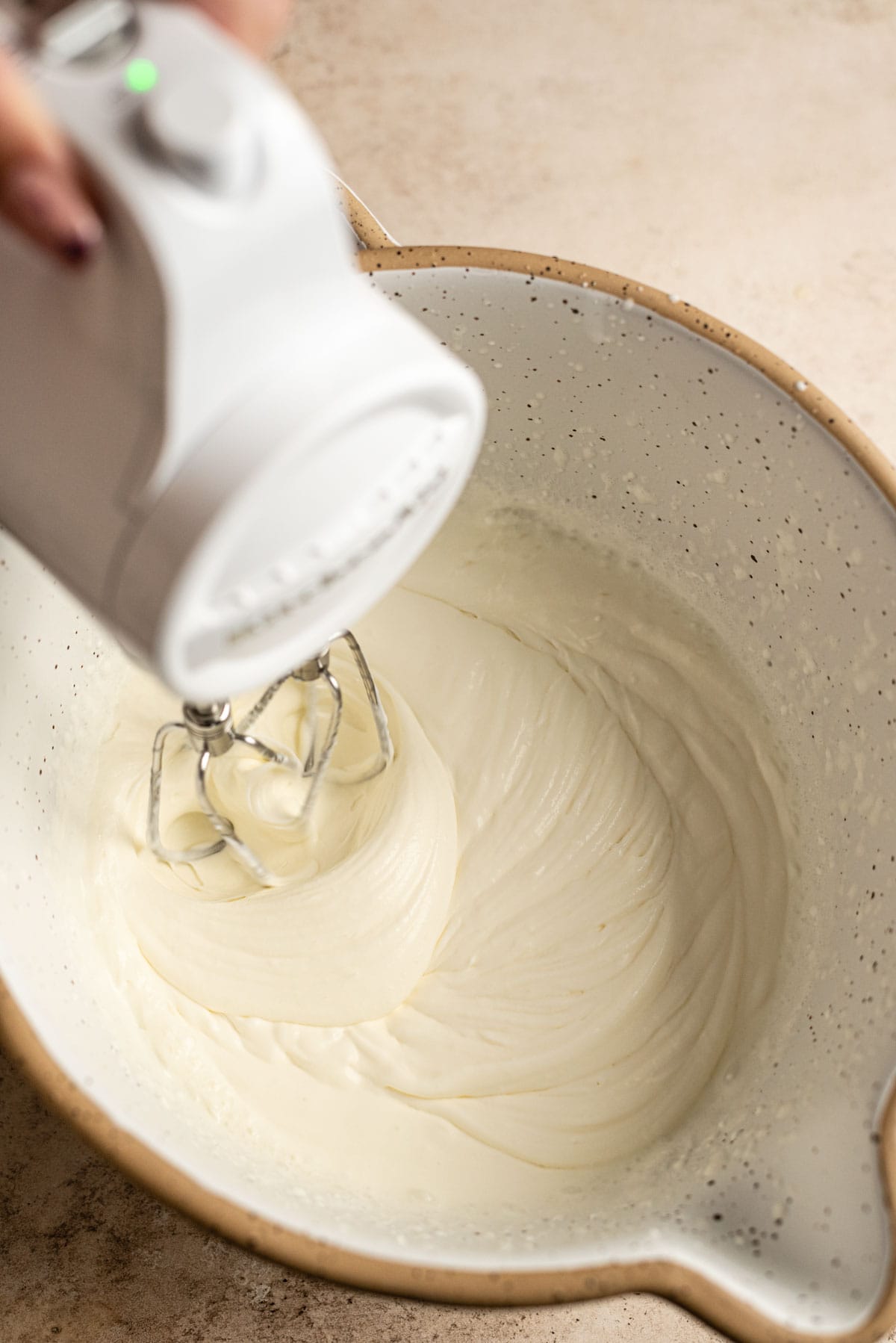 A mixer starting to whip the cream in a bowl.