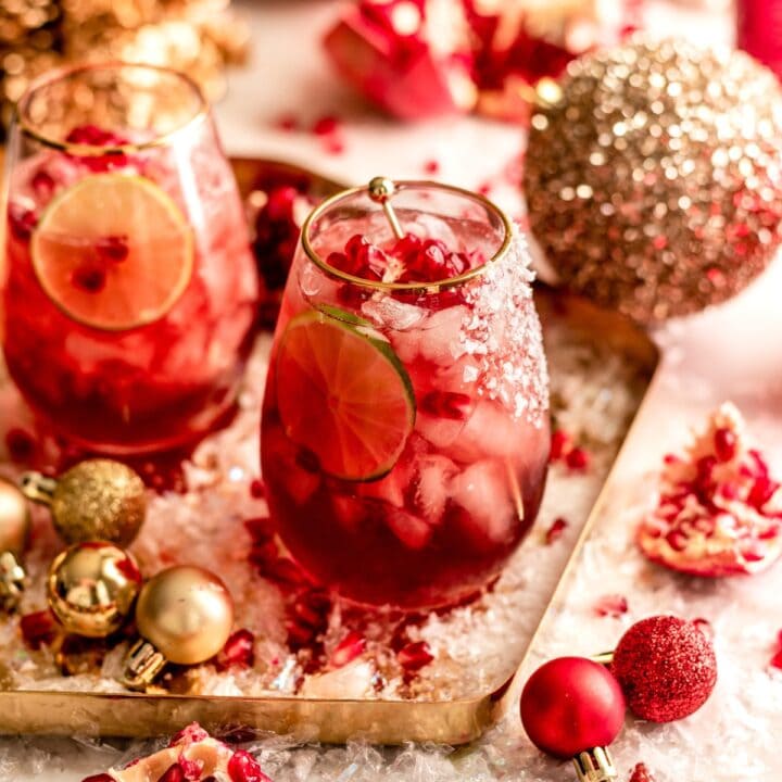 A pomegranate margarita on a gold tray surrounded by ornaments.