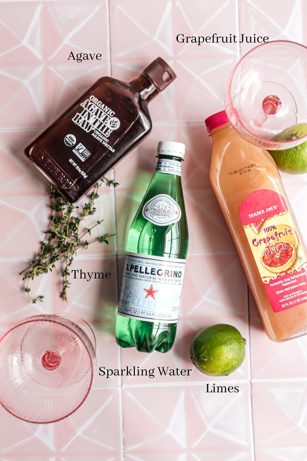 The ingredients for the cocktail on a pink tile table.