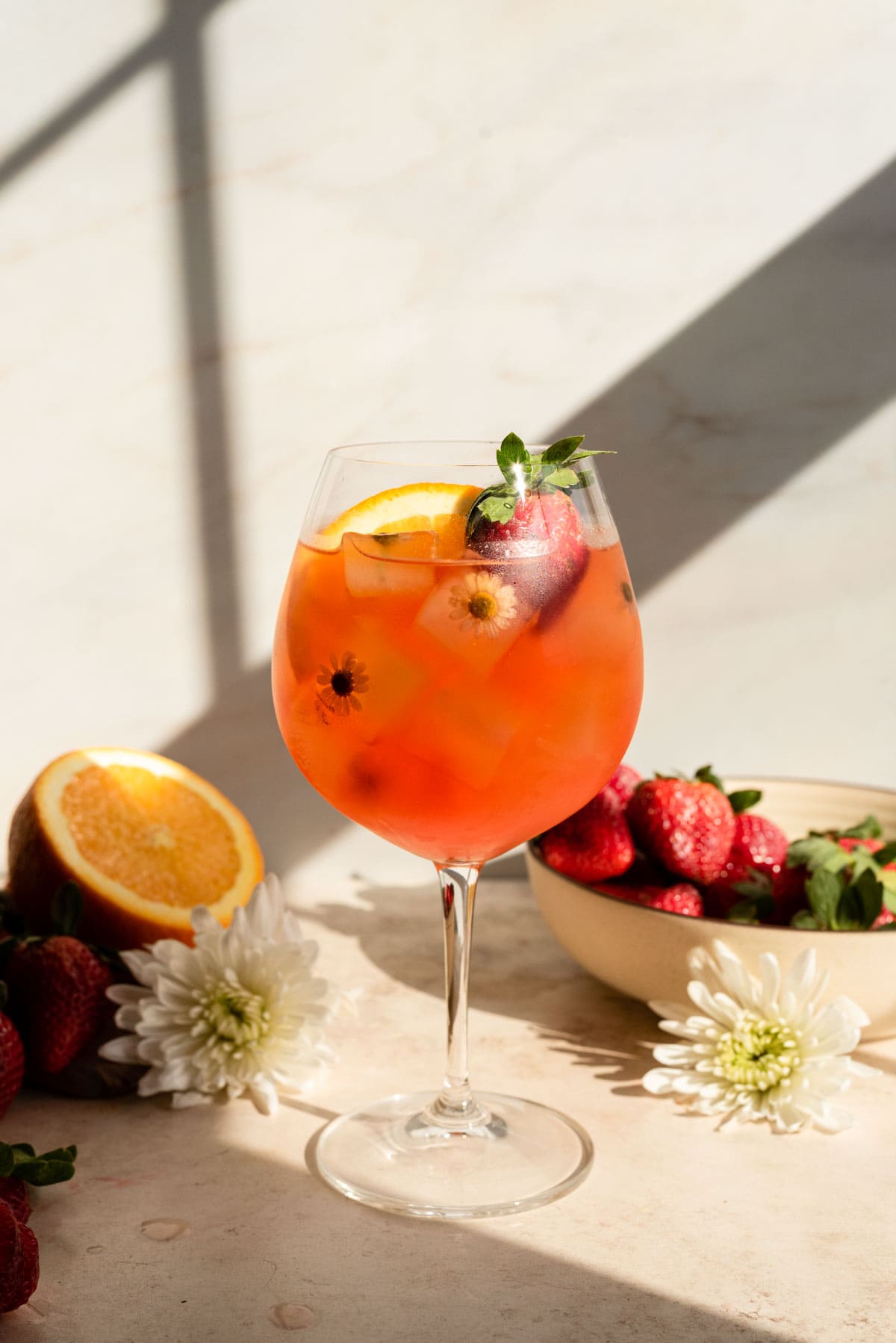 The cocktail has been garnished with an orange slice and a strawberry.