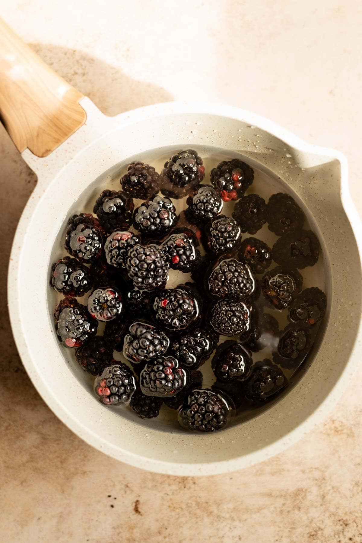 The blackberries, sugar, and water sitting in a small pot.