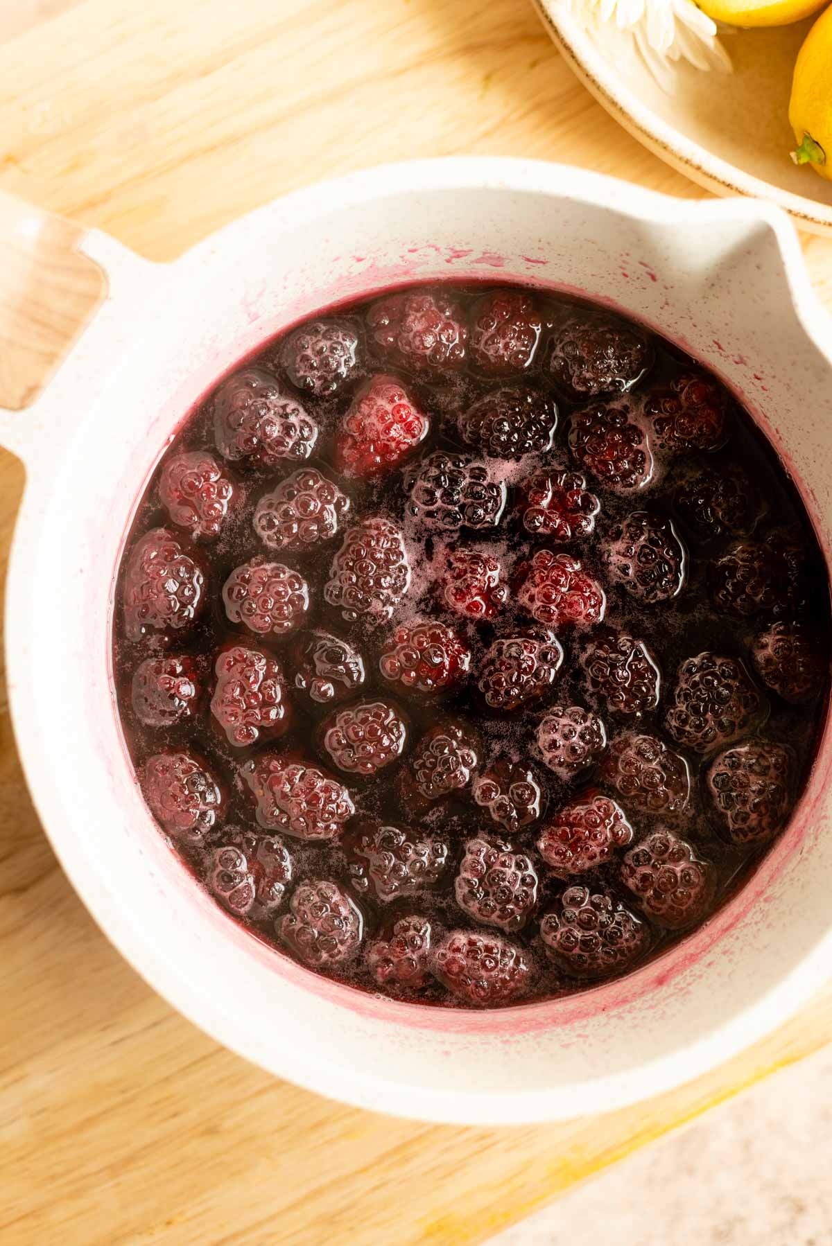 The Cooked blackberries sitting in a small pot.
