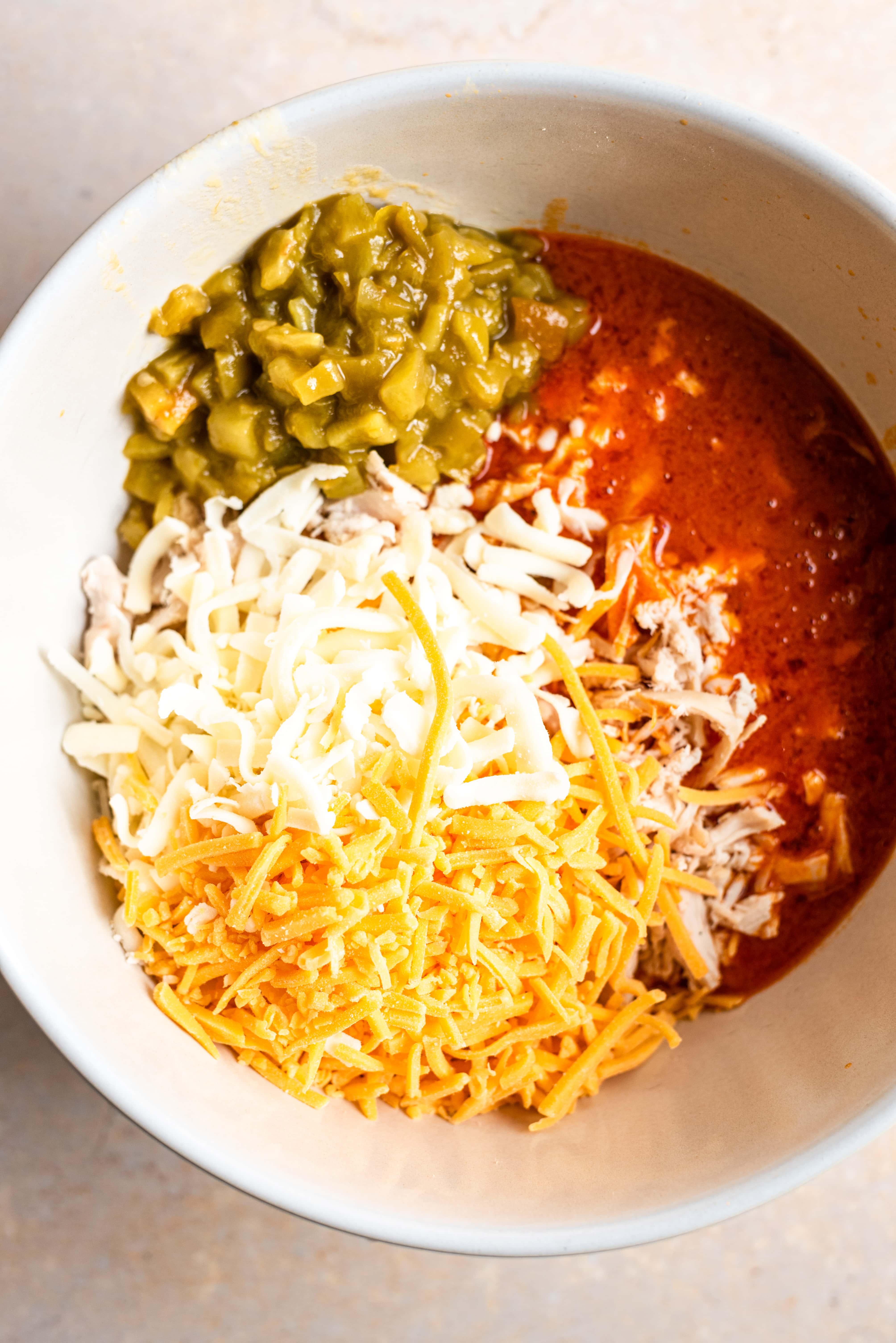 The buffalo sauce, chiles, and cheeses have been added to the bowl with the chicken.