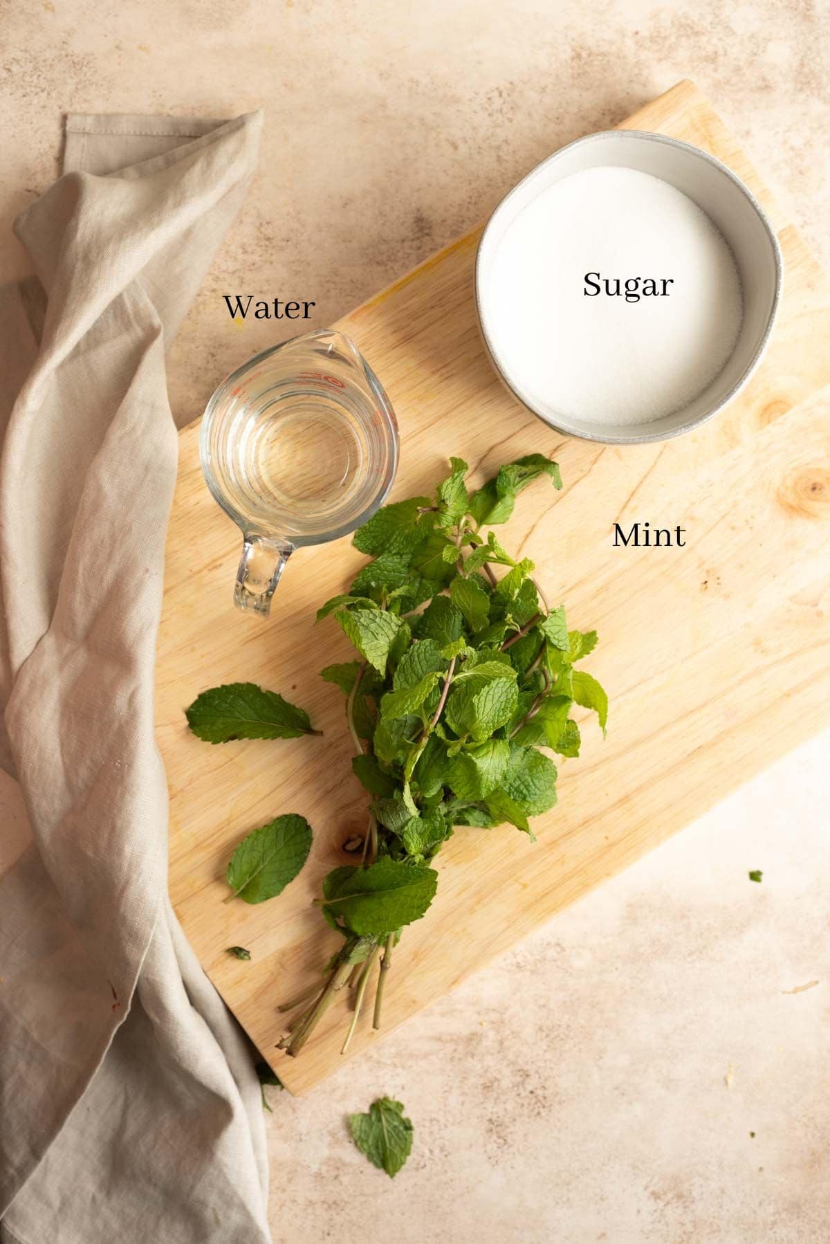 Ingredients for mint simple syrup on a brown table.