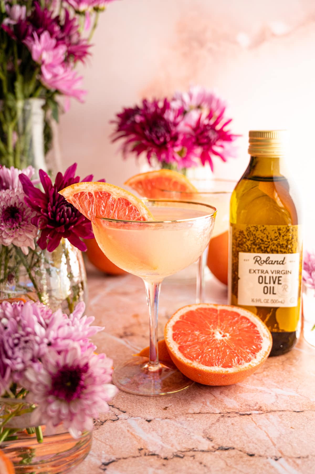 Grapefruit olive oil martini in a curved martini glass surrounded by grapefruit halves.